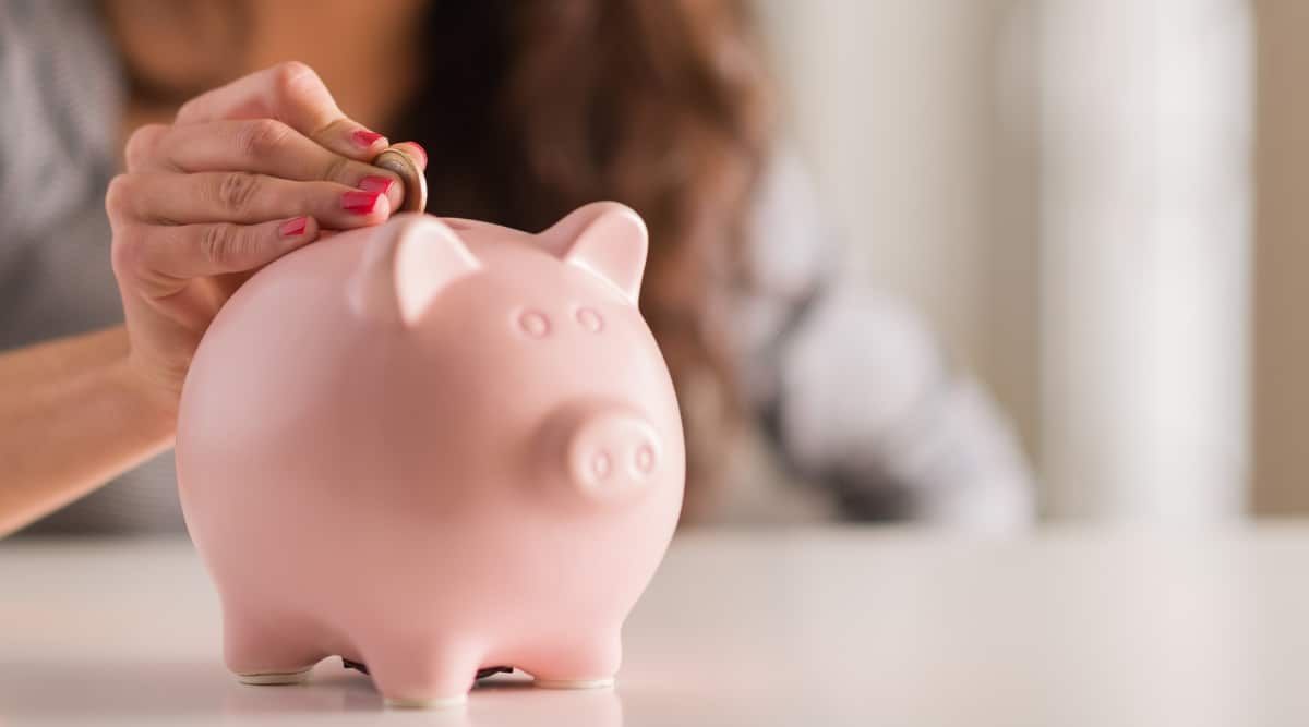 Person putting coins into a piggy bank to save for a rainy day