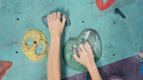 hands climbing rock wall